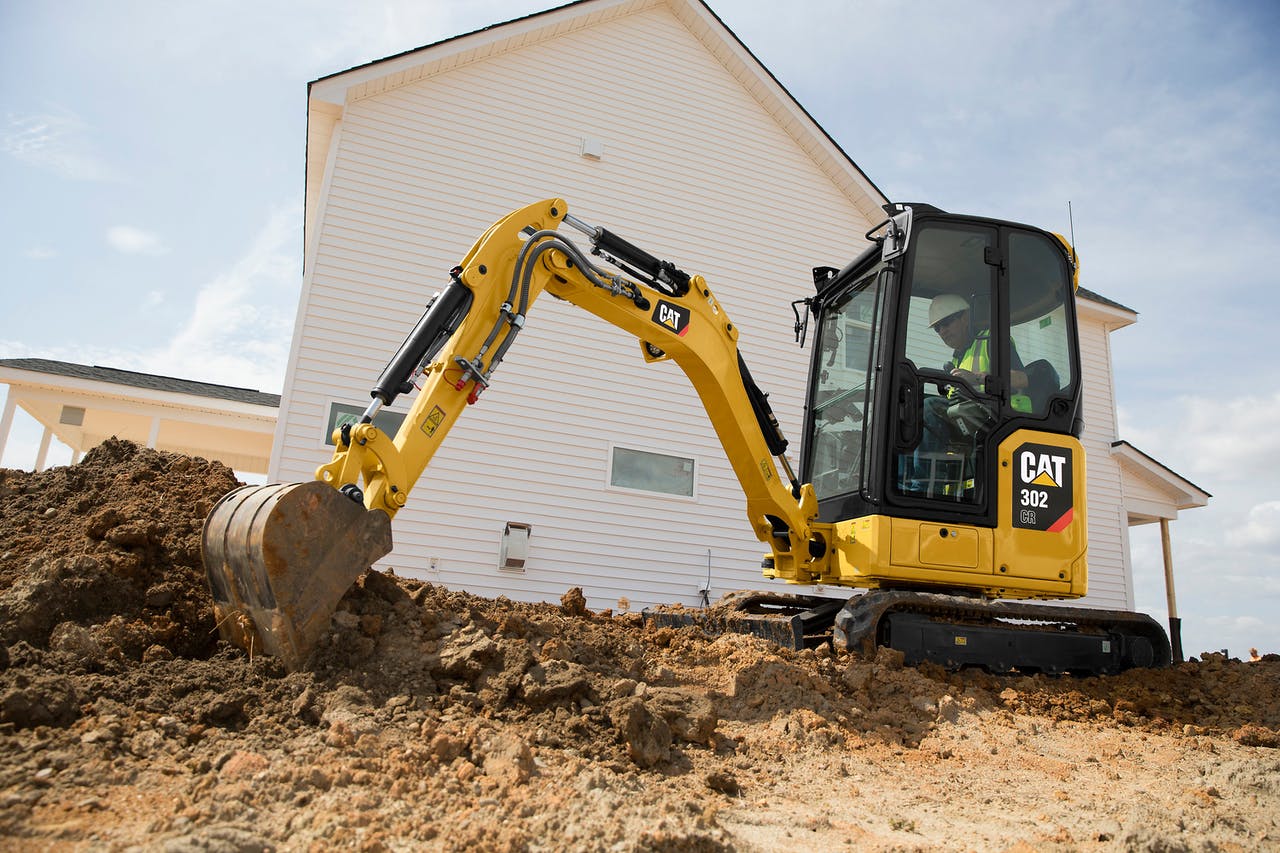 CAT compact mini excavator digging dirt near house